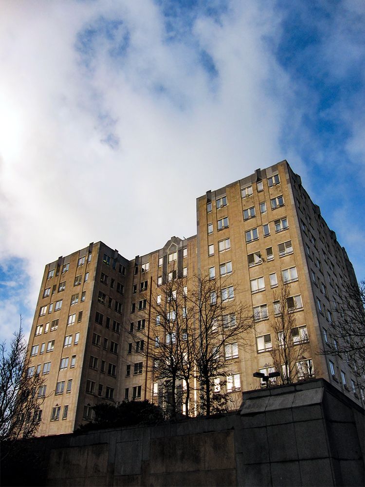 A modern brick building seen from a low angle. In the background a cloudy blue sky.