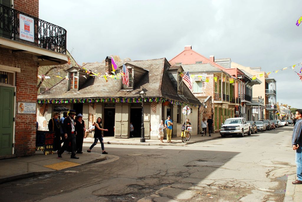 A New Orleans street, with some people walking and stars and Stripes flag hanging on an old building.