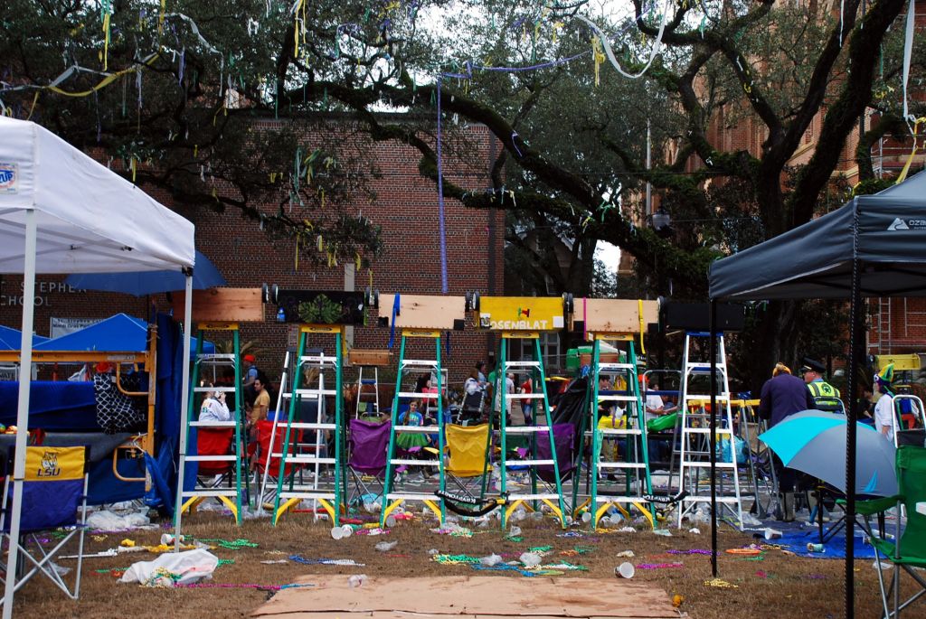 A row of lader for watching a mardi-gras parade, there is a lot of trash all around the street.